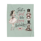 A square fabric throw blanket with a light sage green background, featuring a whimsical illustration of a girl in a pink dress pointing to a nutcracker and a mouse, with the text 'Just a Girl Who Loves Nutcracker' in black and pink script.