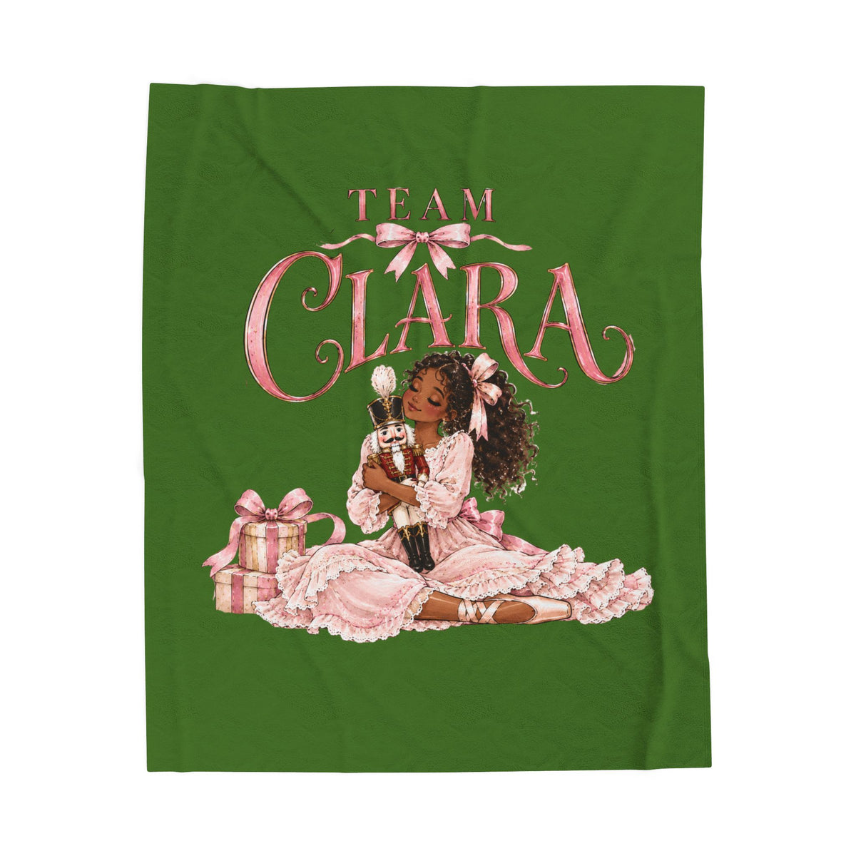 A green blanket featuring a graphic print of a young girl in a pink dress with the text 'TEAM CLARA' above her, accompanied by a gift box.