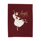 A rectangular dark burgundy fabric item, likely a towel or blanket, featuring a gold and white illustration of a ballerina angel with the text 'Angels The Nutcracker'.