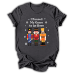 A dark gray graphic t-shirt featuring three colorful nutcracker illustrations and the text 'I Paused My Game to Be Here' in white, displayed against a plain white background.
