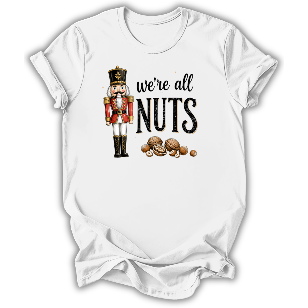 A white short-sleeve crewneck t-shirt with a graphic print of a nutcracker soldier and the text 'we're all NUTS' alongside illustrated walnuts, shown on a plain white background.