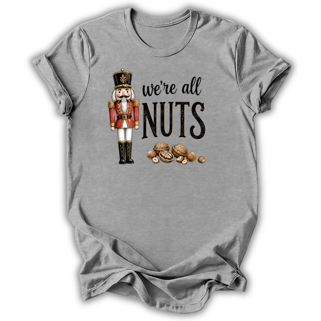A heather gray short-sleeve t-shirt with a graphic print of a nutcracker, the text 'we're all NUTS' in black, and several illustrated walnuts, shown on a plain white background.