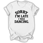 A white short-sleeve crewneck t-shirt with the phrase 'SORRY I'M LATE I WAS DANCING.' printed in black across the chest, shown on a plain white background.