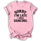 A light pink short-sleeve crewneck t-shirt with the text 'SORRY I'M LATE I WAS DANCING.' printed in black across the front, displayed on a clean white background.