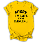 A bright yellow short-sleeve t-shirt with black text reading 'SORRY I'M LATE I WAS DANCING.' on the front, shown against a plain white background.