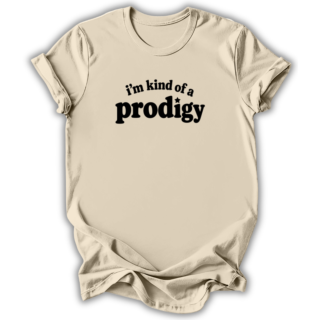 A light beige crewneck t-shirt with a black graphic text print reading 'i'm kind of a prodigy' on the chest, displayed against a clean white background.