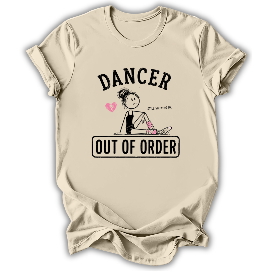 A beige graphic t-shirt featuring a cartoon stick figure dancer with the text 'DANCER STILL SHOWING UP OUT OF ORDER' and a small pink heart, displayed against a clean white background.