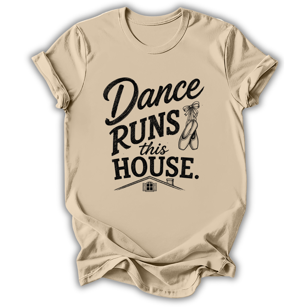 A beige short-sleeve t-shirt with a black graphic print that reads 'Dance Runs This House.' accompanied by ballet shoes and a small house illustration, displayed on a clean white background.