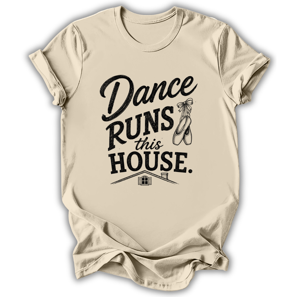 A beige short-sleeve t-shirt with a black graphic print that reads 'Dance Runs This House.' accompanied by a ballet shoe illustration, displayed on a clean white background.