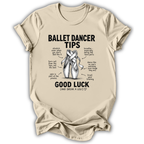 A beige crewneck t-shirt with a black graphic print titled 'Ballet Dancer Tips' featuring an illustration of ballet pointe shoes and humorous tips with handwritten-style text, shown on a plain white background.