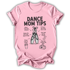 A light pink short-sleeve t-shirt with a black graphic print titled 'DANCE MOM TIPS' featuring illustrations of ballet slippers and dance-related tips, shown on a plain white background.