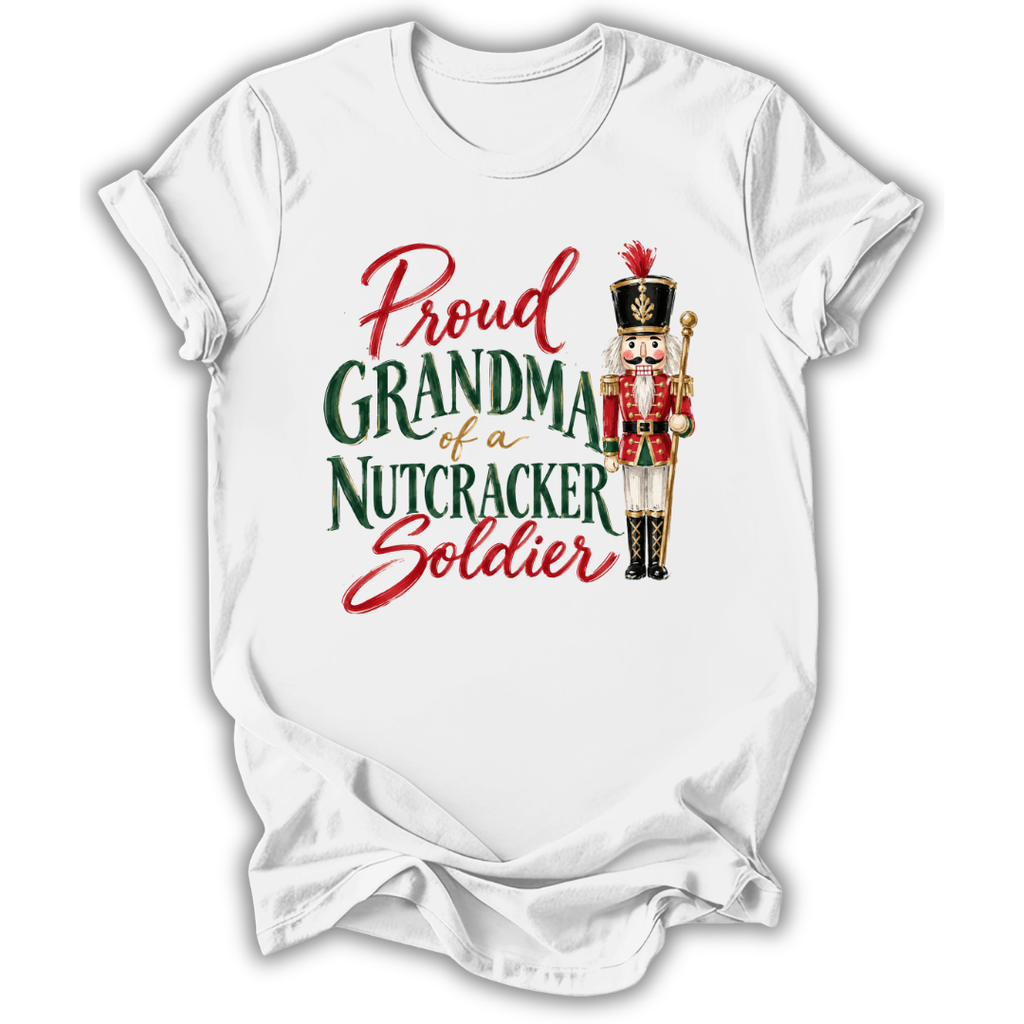 A white short-sleeve crewneck t-shirt with a graphic print that reads 'Proud GRANDMA of a NUTCRACKER Soldier' in red and green lettering, accompanied by an illustration of a nutcracker soldier.