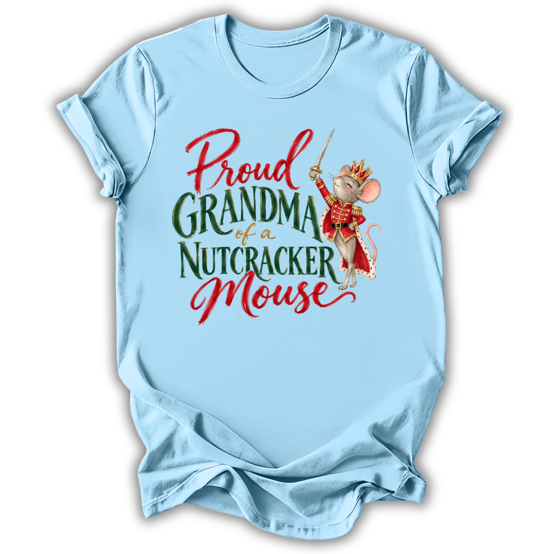 A light blue short-sleeve t-shirt with a graphic print that reads 'Proud GRANDMA of a NUTCRACKER Mouse' in red and green lettering, featuring an illustration of a nutcracker mouse in a red and gold costume.