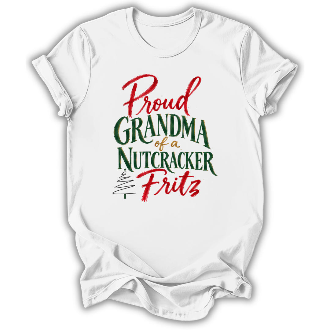 A white short-sleeve crewneck t-shirt with a festive graphic reading 'Proud Grandma of a Nutcracker Fritz' in red and green lettering, displayed on a clean white background.