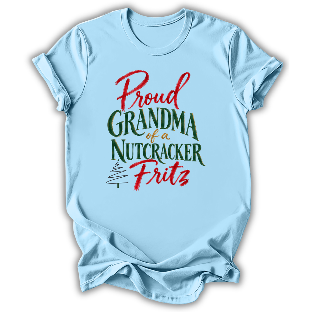 A light blue short-sleeve t-shirt with a festive graphic that reads 'Proud Grandma of a Nutcracker Fritz' in red and green lettering, displayed on a clean white background.