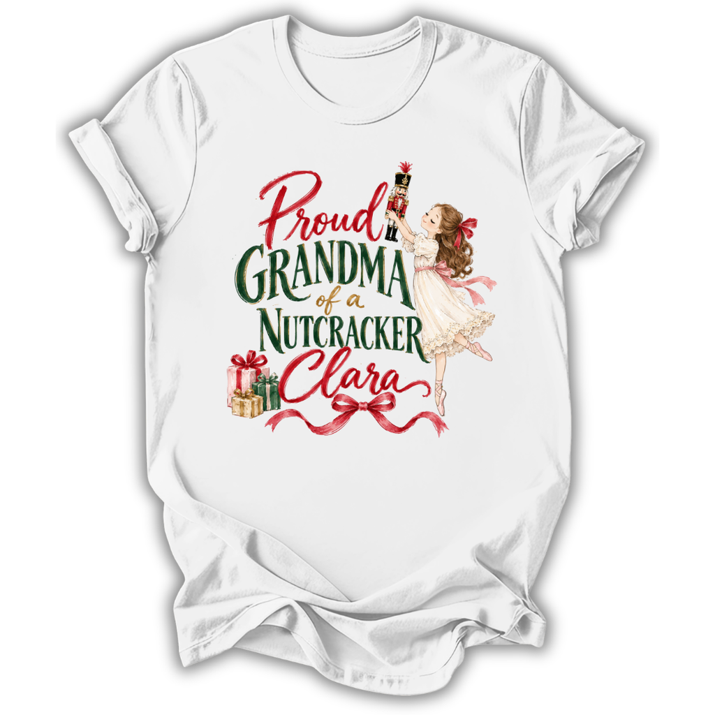 A white short-sleeve t-shirt with a vintage-style Christmas graphic that reads 'Proud GRANDMA of a Nutcracker Clara' in red and green lettering, featuring an illustration of a ballerina girl, a nutcracker, and wrapped gifts.