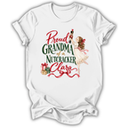 A white short-sleeve t-shirt with a vintage-style Christmas graphic that reads 'Proud GRANDMA of a Nutcracker Clara' in red and green lettering, featuring an illustration of a ballerina girl, a nutcracker, and wrapped gifts.