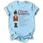 A light blue short-sleeve t-shirt with a custom Christmas graphic on the front, featuring a nutcracker illustration and the text 'Clara's Christmas Eve' followed by a poem. The t-shirt is displayed flat against a plain white background.