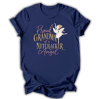 A navy blue short-sleeve t-shirt with a graphic print on the front. The graphic features a white ballerina nutcracker and text that reads 'Proud GRANDMA of a NUTCRACKER Angel' in gold and pink lettering, set against a plain white background.