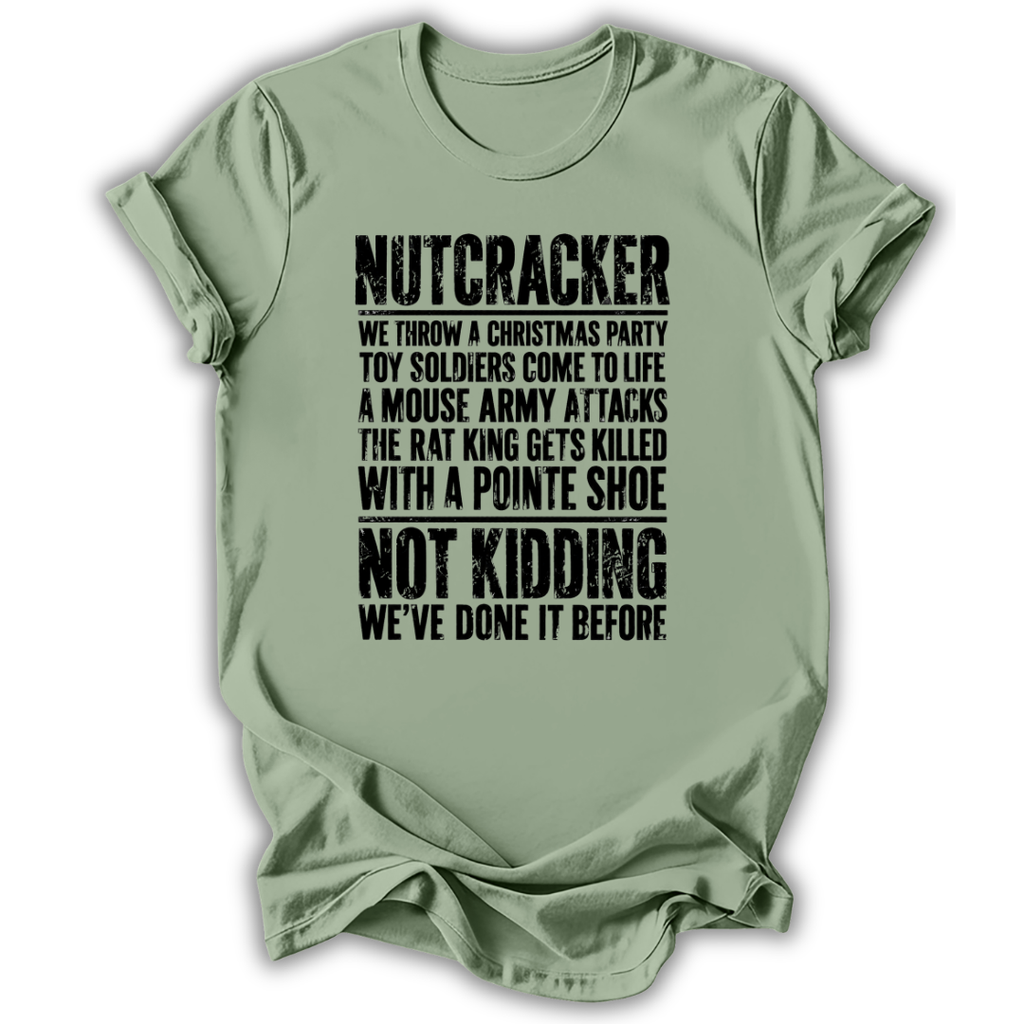 A sage green short-sleeve t-shirt with a humorous, distressed black text graphic on the front, displayed against a clean white background.