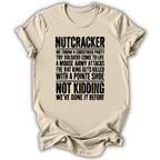 A beige short-sleeve t-shirt with a humorous Christmas-themed text graphic printed in black distressed font, displayed against a clean white background.