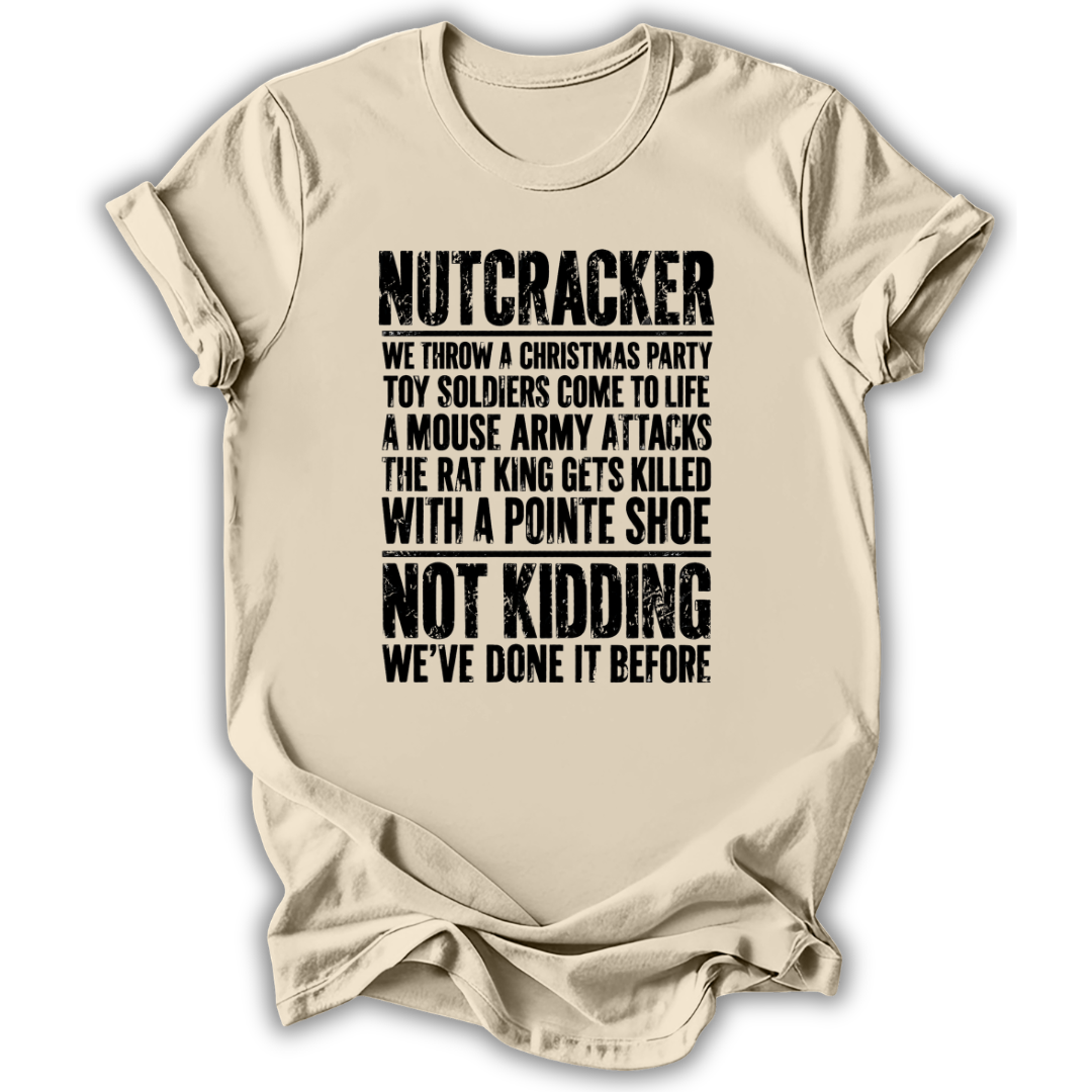 A beige short-sleeve t-shirt with a humorous Christmas-themed text graphic printed in black distressed font, displayed against a clean white background.