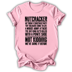 A light pink short-sleeve t-shirt with a humorous Christmas-themed text graphic printed in black distressed font on the front, displayed against a clean white background.