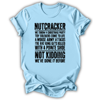A light blue short-sleeve t-shirt with a humorous Christmas-themed text graphic printed in black on the front, displayed against a clean white background.
