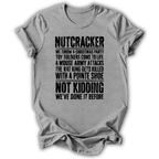 A light gray heather crewneck t-shirt with a distressed black graphic print of the 'Nutcracker' holiday story, displayed on a clean white background.
