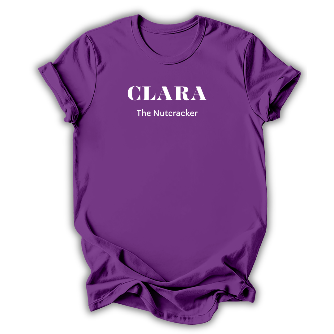 Purple short-sleeve crewneck t-shirt with white printed text reading 'CLARA The Nutcracker' on the chest, shown on a plain white background.