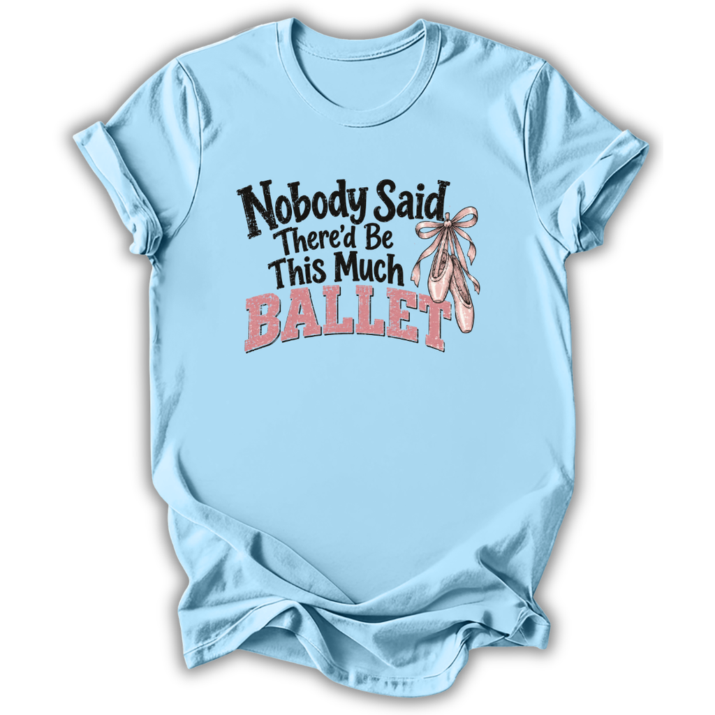 A light blue short-sleeve t-shirt with a graphic on the front that reads 'Nobody Said There'd Be This Much BALLET' in black and pink lettering, accompanied by an illustration of pink ballet slippers with a ribbon. The t-shirt is shown against a plain white background with a soft drop shadow.