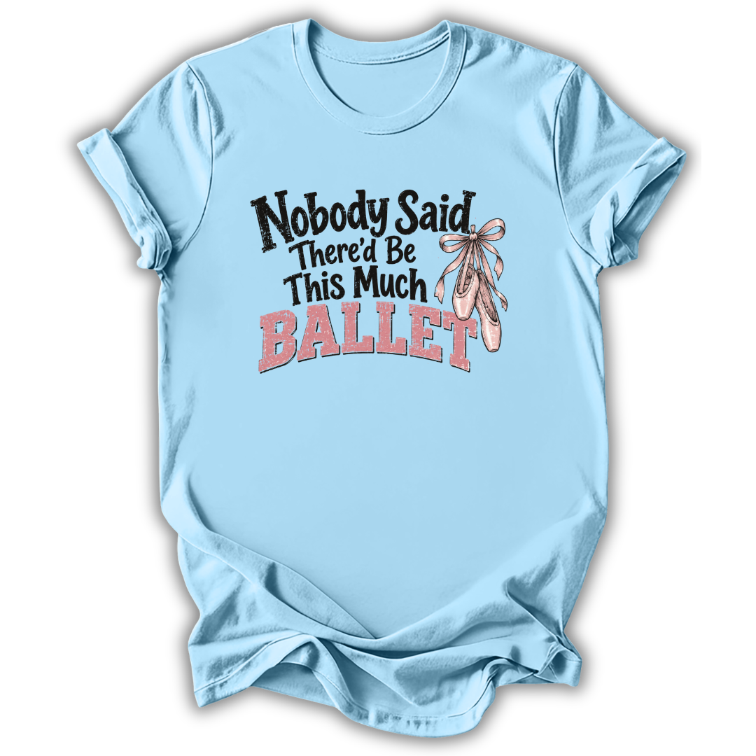 A light blue short-sleeve t-shirt with a graphic on the front that reads 'Nobody Said There'd Be This Much BALLET' in black and pink lettering, accompanied by an illustration of pink ballet slippers with a ribbon. The t-shirt is shown against a plain white background with a soft drop shadow.