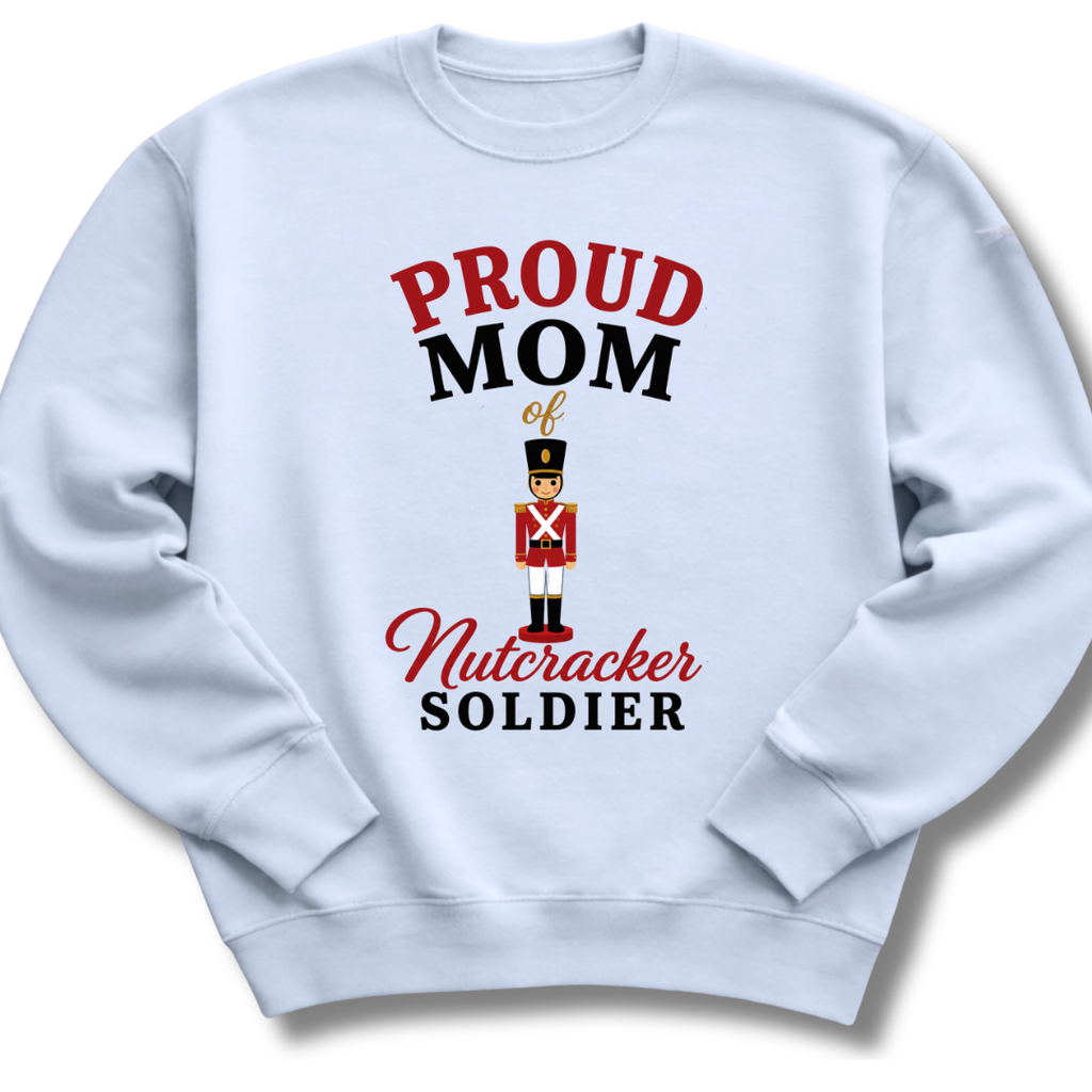 A light blue crewneck sweatshirt featuring a graphic print that reads 'PROUD MOM of Nutcracker SOLDIER' in red and black lettering, with an illustration of a nutcracker soldier in the center.