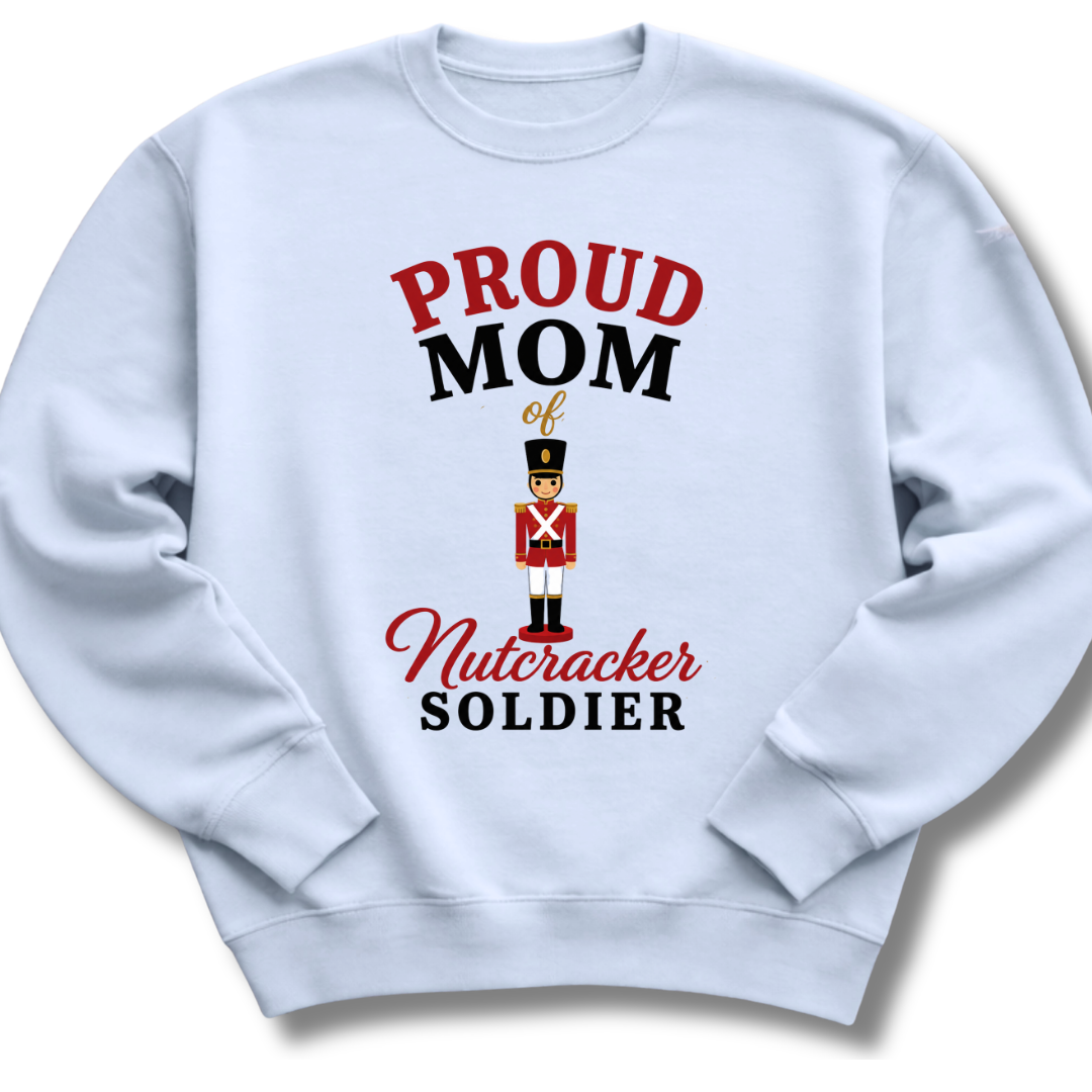 A light blue crewneck sweatshirt featuring a graphic print that reads 'PROUD MOM of Nutcracker SOLDIER' in red and black lettering, with an illustration of a nutcracker soldier in the center.