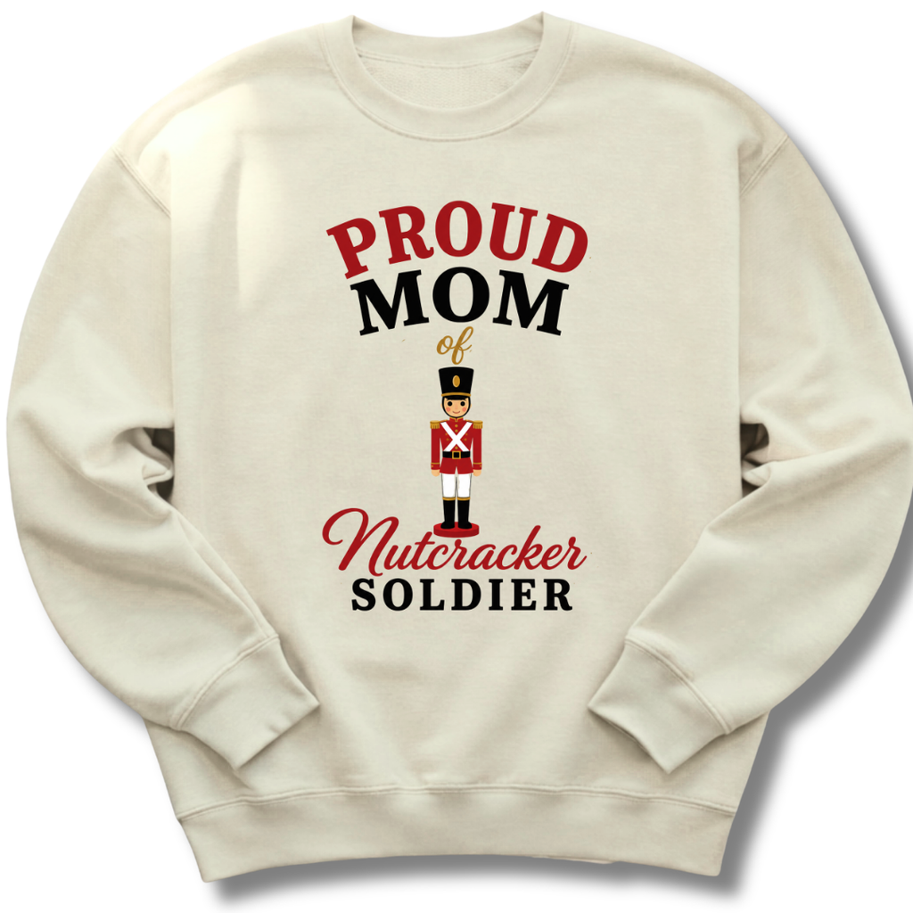 An off-white crewneck sweatshirt featuring a graphic print that reads 'PROUD MOM of Nutcracker SOLDIER' in red and black lettering, with an illustration of a nutcracker soldier in the center.