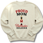 An off-white crewneck sweatshirt featuring a graphic print that reads 'PROUD MOM of Nutcracker SOLDIER' in red and black lettering, with an illustration of a nutcracker soldier in the center.