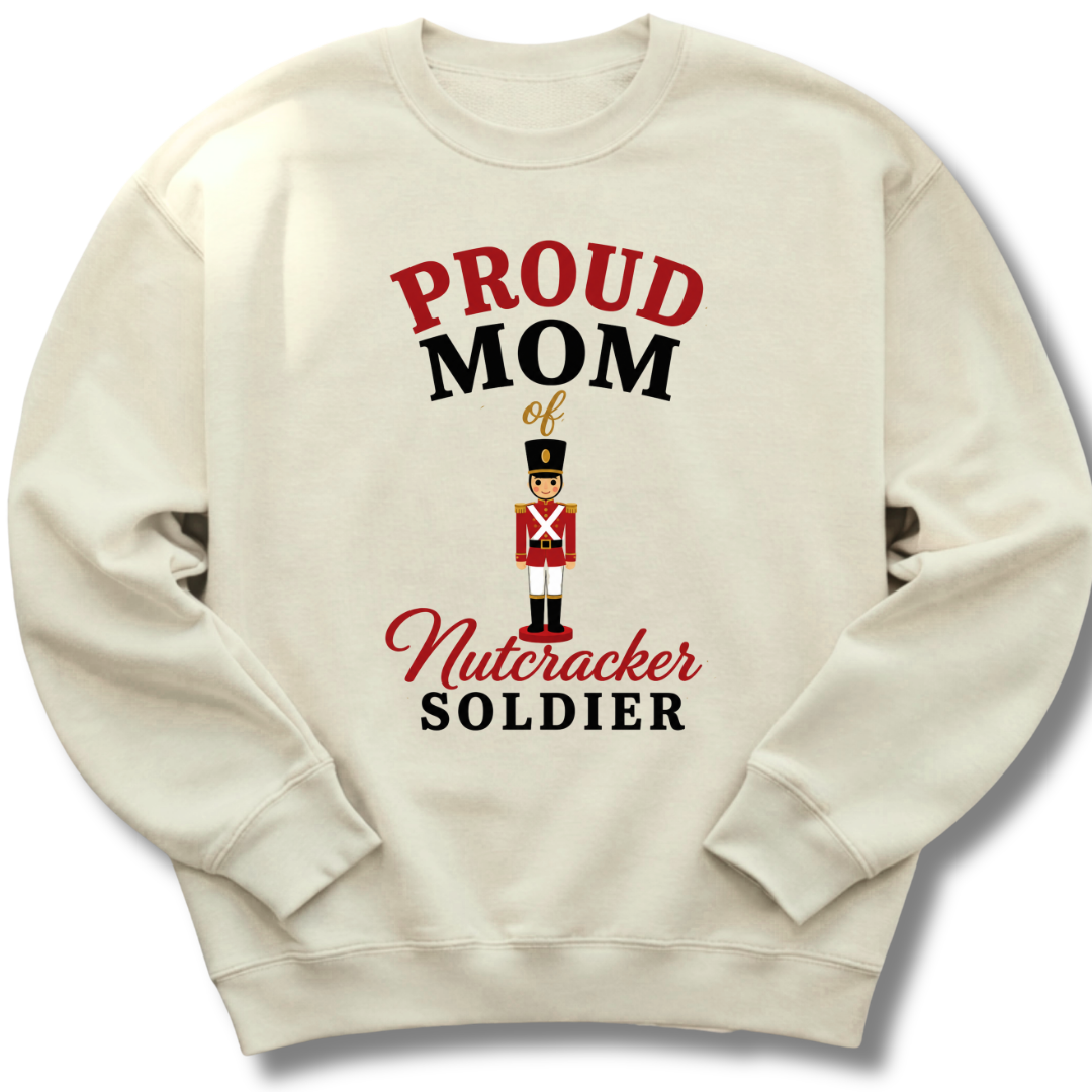 An off-white crewneck sweatshirt featuring a graphic print that reads 'PROUD MOM of Nutcracker SOLDIER' in red and black lettering, with an illustration of a nutcracker soldier in the center.