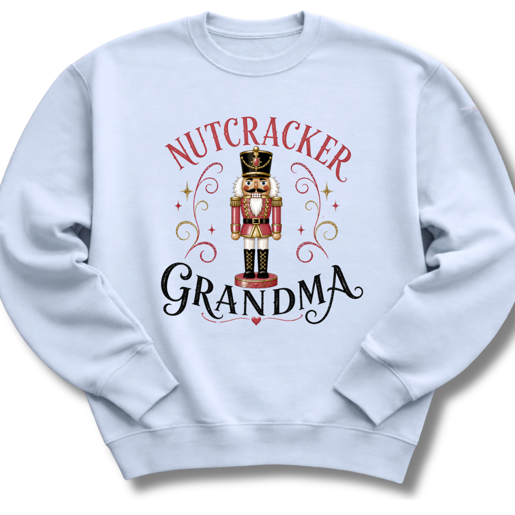 A light blue crewneck sweatshirt featuring a festive graphic print of a nutcracker soldier with the words 'NUTCRACKER GRANDMA' in red and black lettering.