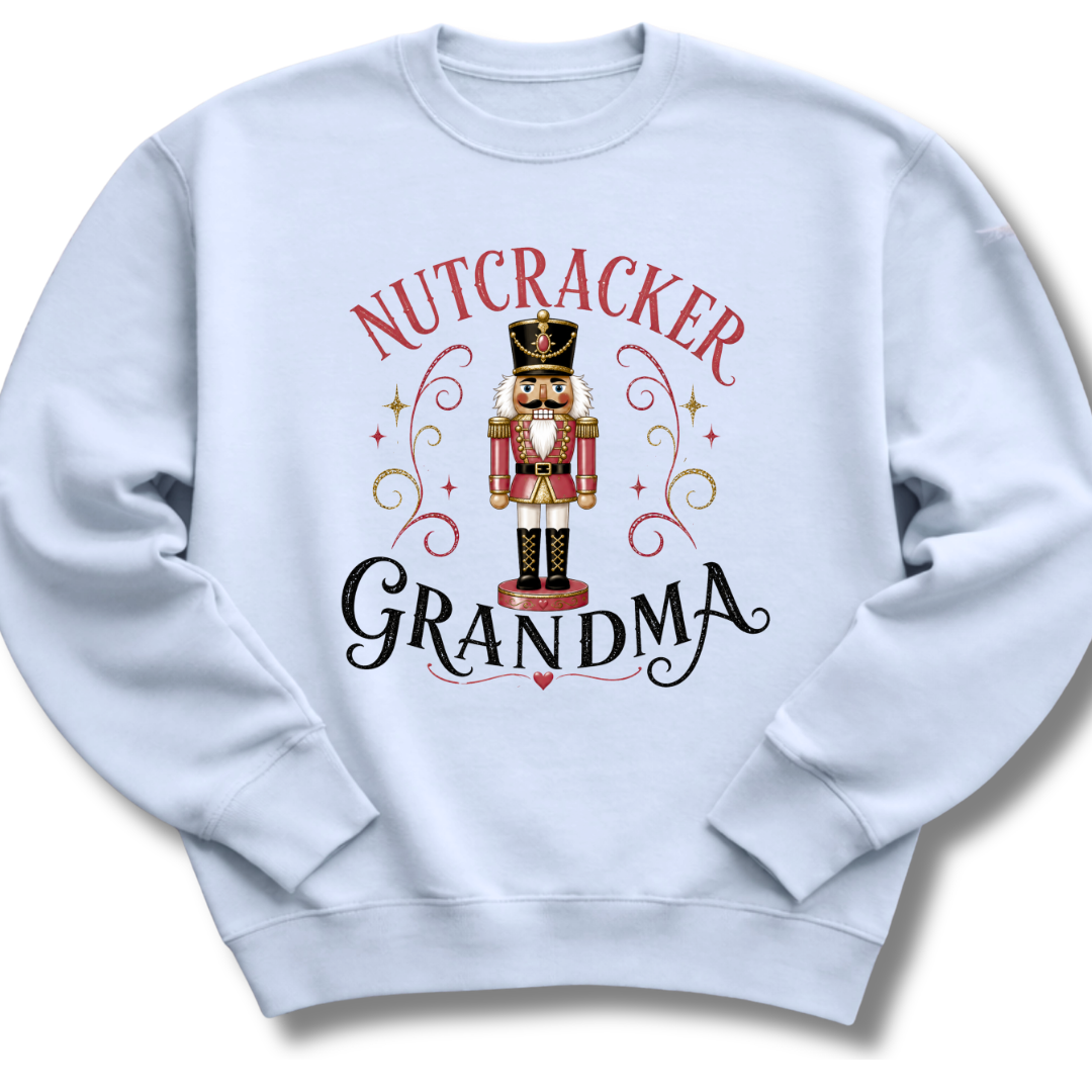 A light blue crewneck sweatshirt featuring a festive graphic print of a nutcracker soldier with the words 'NUTCRACKER GRANDMA' in red and black lettering.