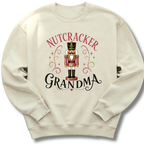 An off-white crewneck sweatshirt featuring a festive graphic of a nutcracker soldier with the words 'NUTCRACKER GRANDMA' in red and black lettering.