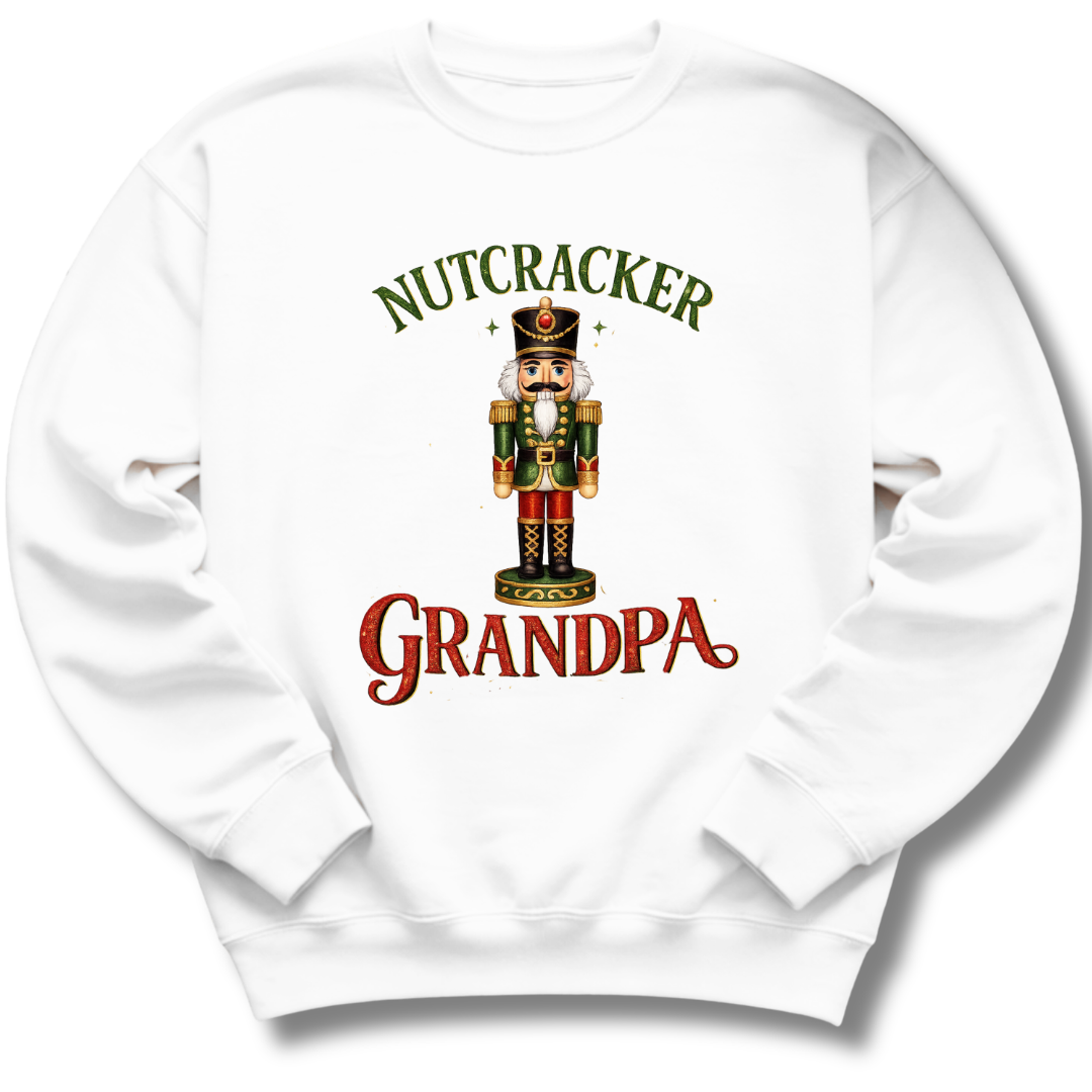 A white crewneck sweatshirt featuring a graphic print of a nutcracker soldier with the text 'NUTCRACKER GRANDPA' in green and red lettering.