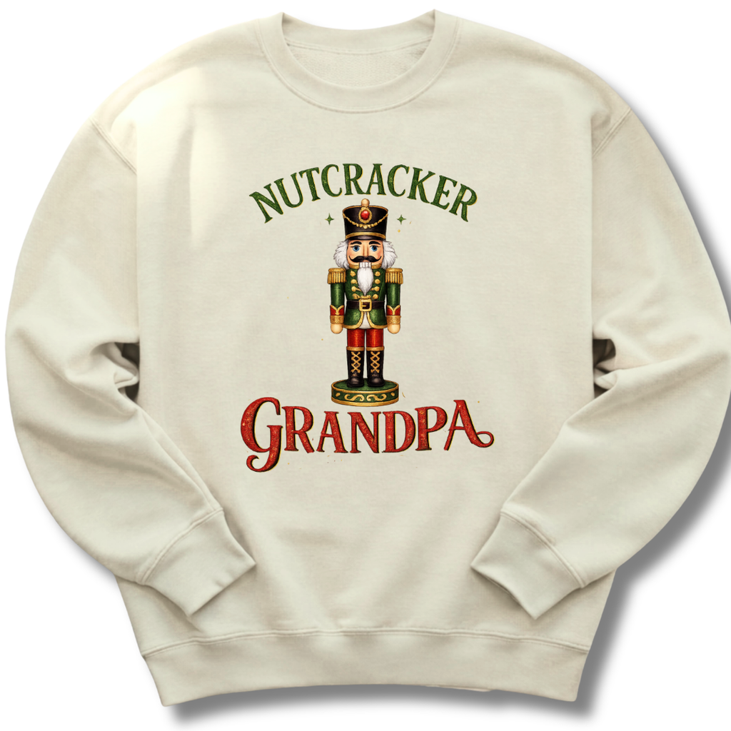 An off-white crewneck sweatshirt featuring a festive graphic of a nutcracker soldier with the text 'NUTCRACKER GRANDPA' in green and red lettering.