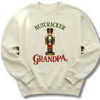 An off-white crewneck sweatshirt featuring a festive graphic of a nutcracker soldier with the text 'NUTCRACKER GRANDPA' in green and red lettering.