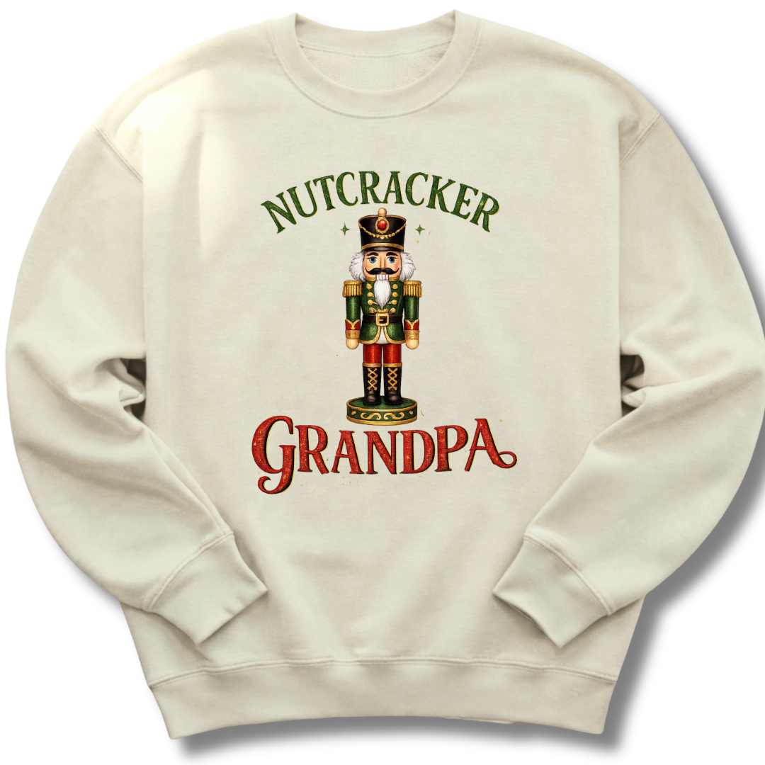An off-white crewneck sweatshirt featuring a festive graphic of a nutcracker soldier with the text 'NUTCRACKER GRANDPA' in green and red lettering.