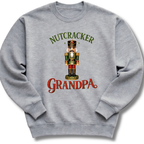 A heather gray crewneck sweatshirt featuring a graphic of a nutcracker soldier with the text 'NUTCRACKER GRANDPA' in green and red lettering.
