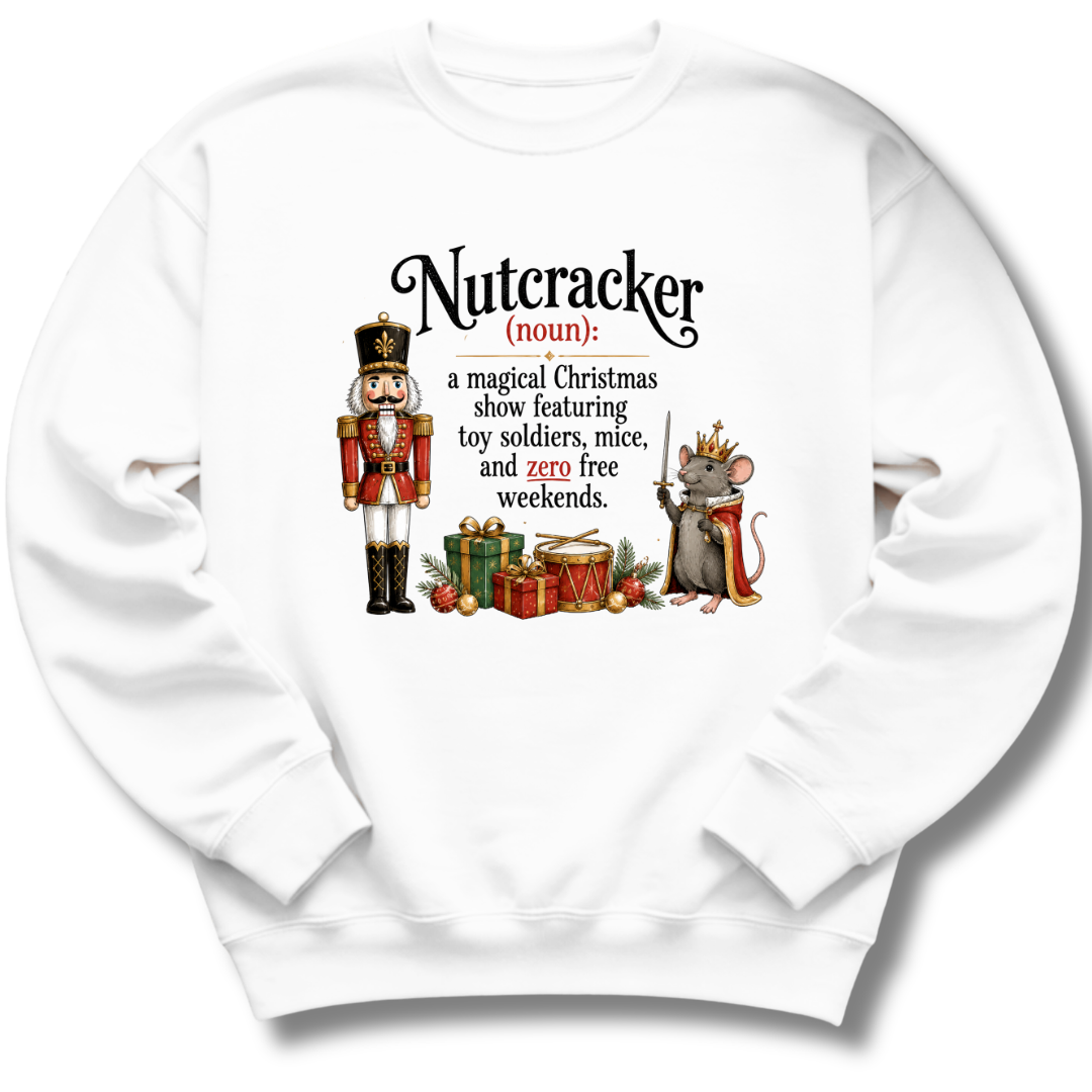 A white crewneck sweatshirt featuring a humorous dictionary-style definition of 'Nutcracker' printed on the chest. The graphic includes a traditional nutcracker soldier on the left and a crowned mouse on the right, surrounded by Christmas gifts and ornaments.