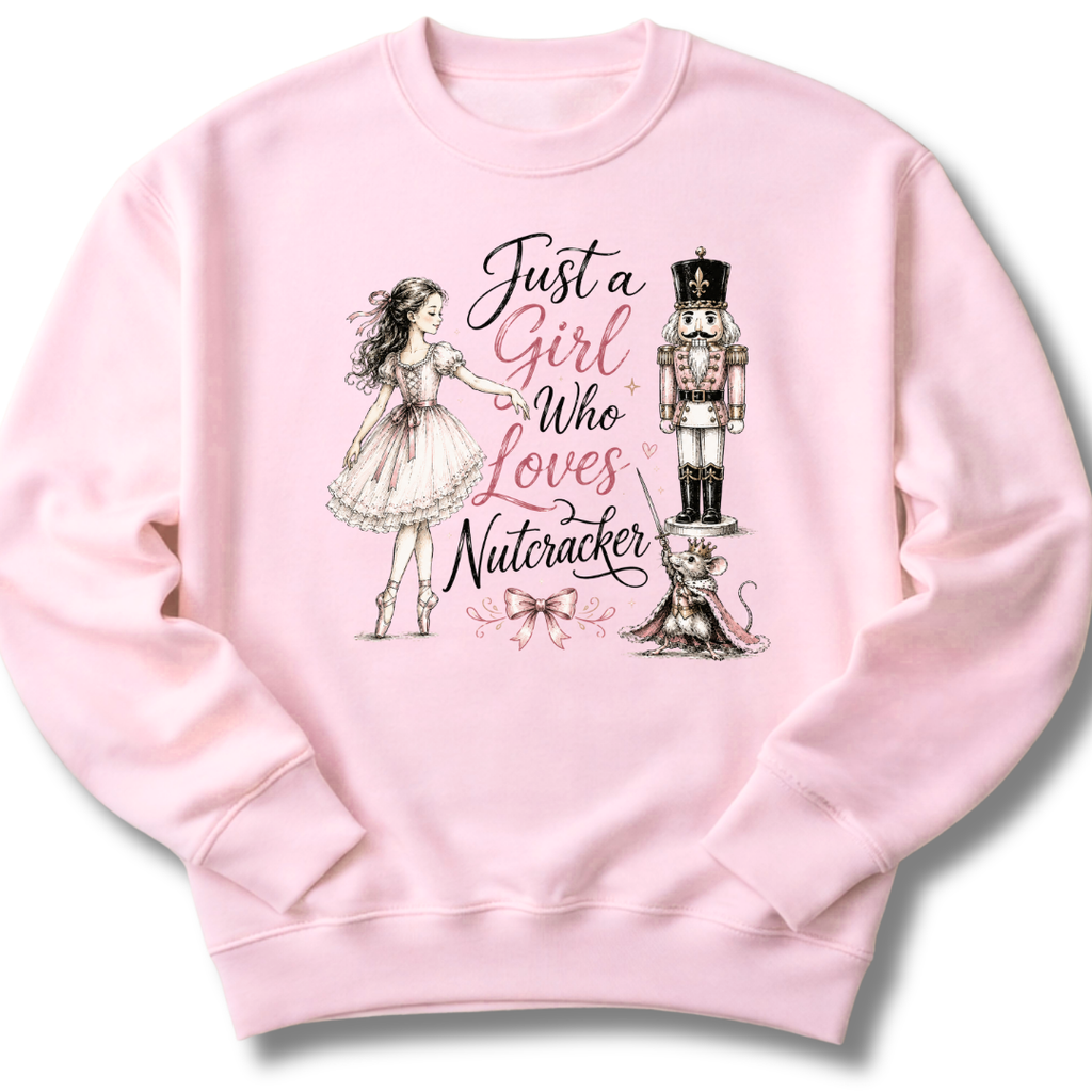 A light pink crewneck sweatshirt featuring a graphic print of a ballerina, a nutcracker, a cat, and the text 'Just a Girl Who Loves Nutcracker' in black and pink script.