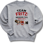 A heather gray crewneck sweatshirt featuring a graphic print on the front with the text 'TEAM FRITZ: BREAKING TOYS SINCE ACT I' and a cartoon illustration of a broken nutcracker and toy pieces.