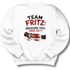 A white crewneck sweatshirt featuring a graphic print on the front with the text 'TEAM FRITZ: BREAKING TOYS SINCE ACT I' and an illustration of a broken nutcracker and toy pieces.