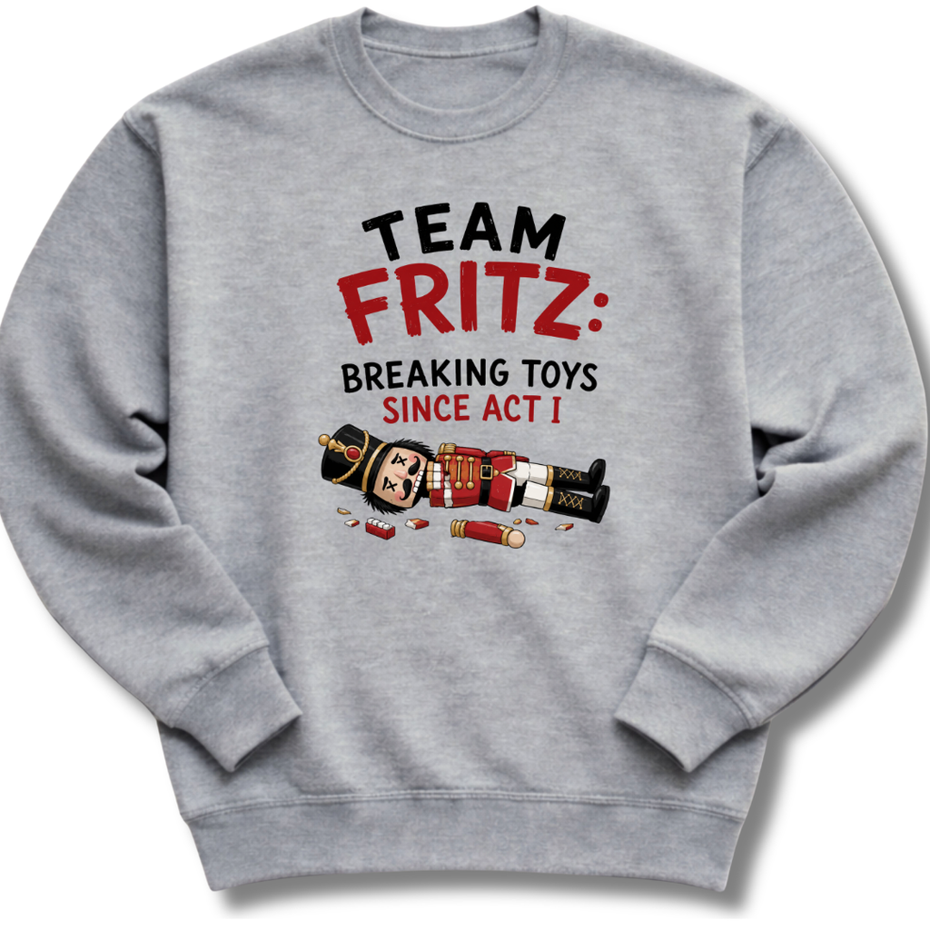 A heather gray crewneck sweatshirt featuring a graphic print on the front with the text 'TEAM FRITZ: BREAKING TOYS SINCE ACT I' and a cartoon illustration of a broken nutcracker and toy pieces.